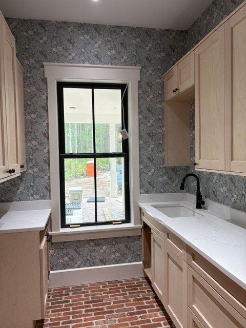 Blue bird and blossom wallpaper in a laundry room with brick floor and black window trim installed by Jeff Handyman