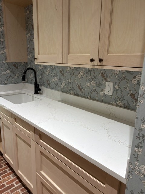 Blue bird and blossom wallpaper behind a laundry room sink and white quartz countertop by Jeff Handyman