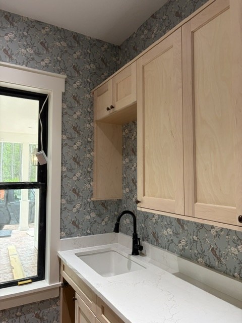 Blue bird and blossom wallpaper wrapped around a laundry room window and cabinets by Jeff Handyman