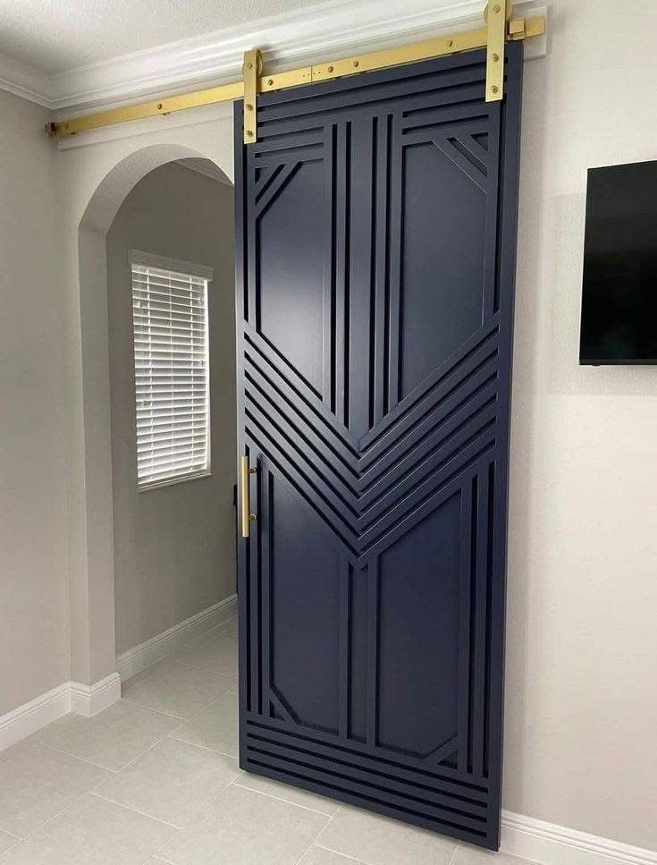 Blue barn door with wave-pattern paneling and black track hardware