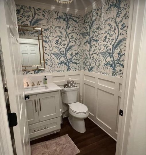 Blue floral wallpaper above white wainscoting in a powder room by Jeff Handyman