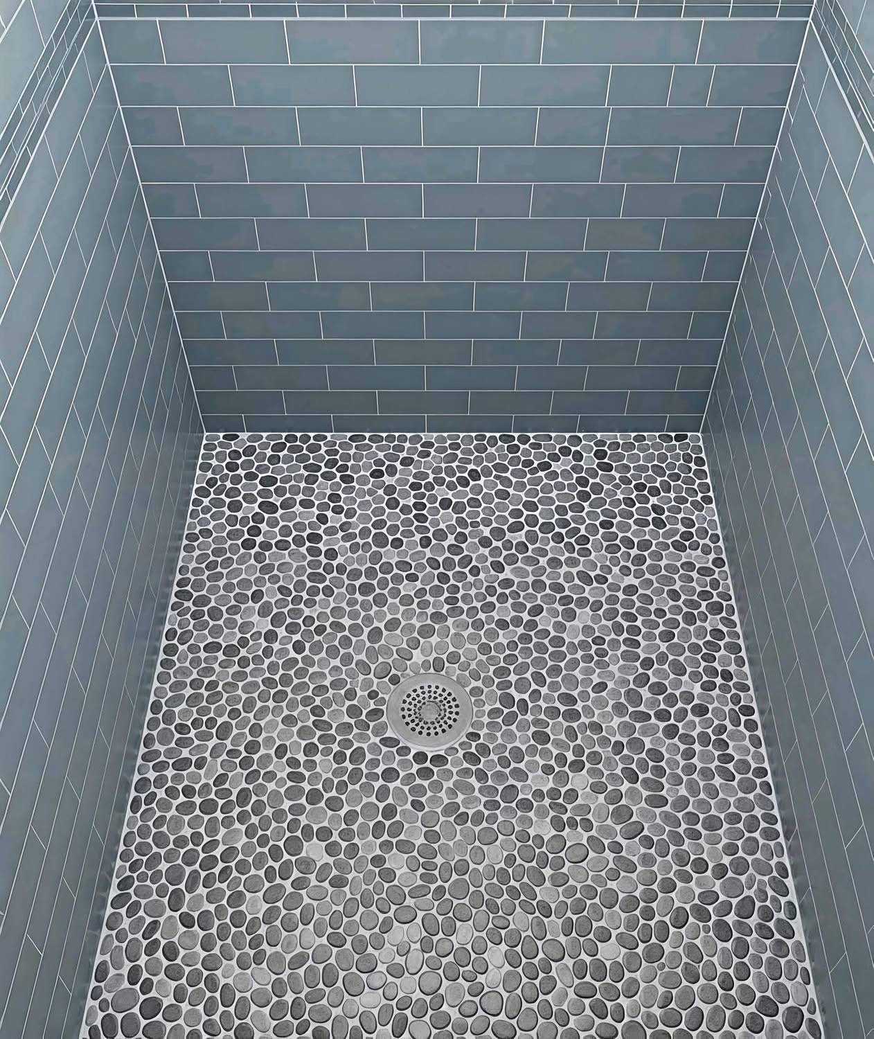 Walk-in shower with deep blue hexagon penny tile floor and matching blue subway tile walls