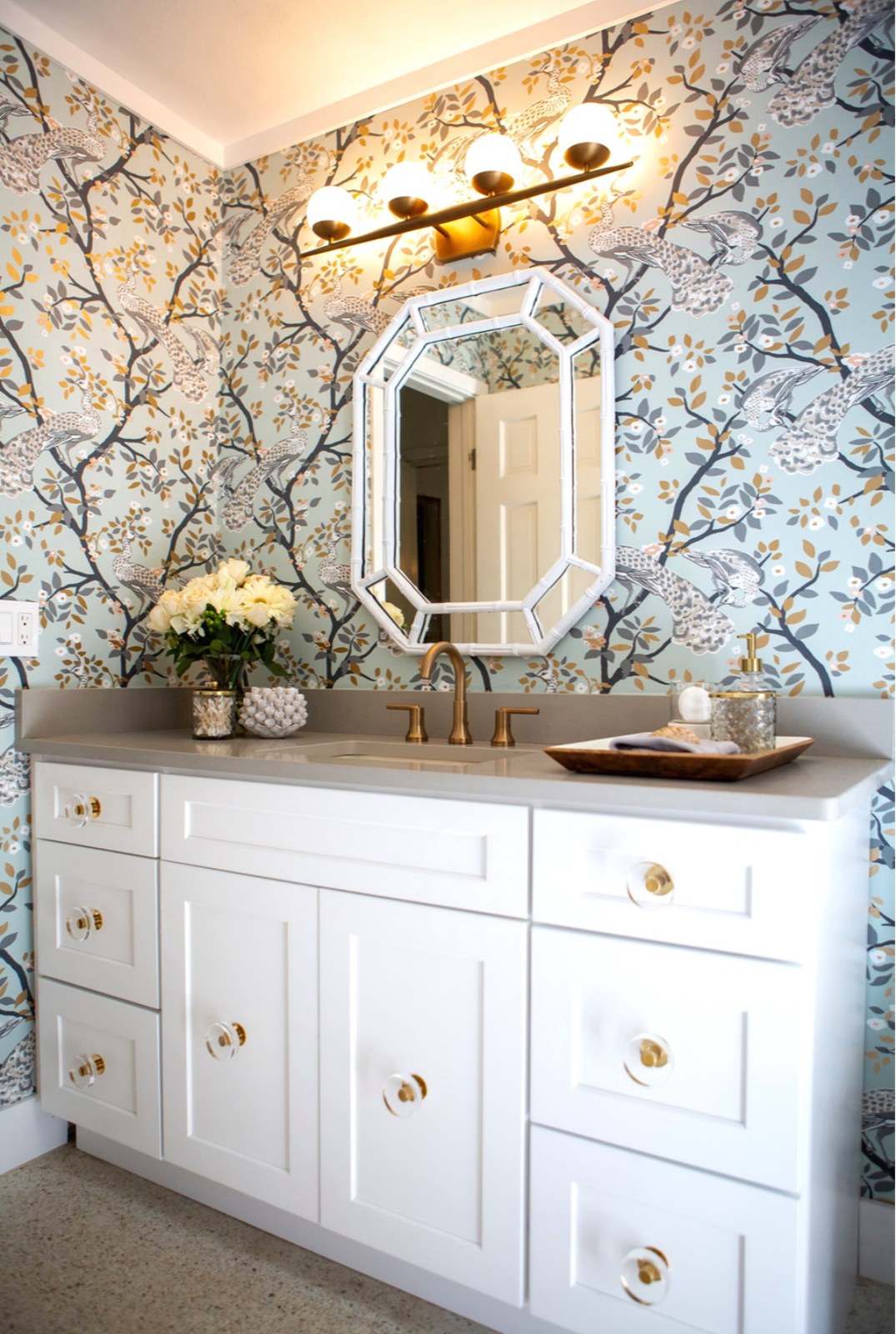 Botanical leaf wallpaper installed in a bathroom with double vanity and octagonal mirror by Jeff Handyman