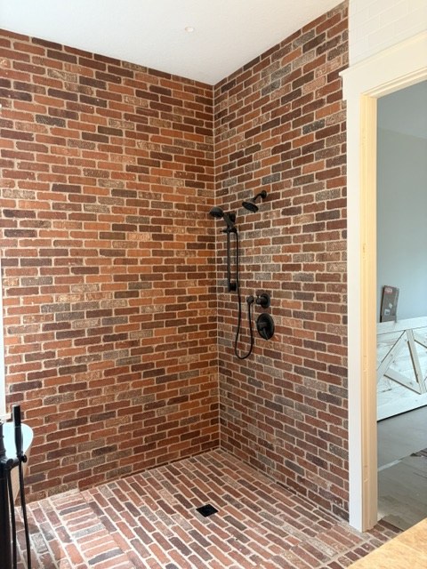 Walk-in shower with reclaimed-look brick walls, brick floor, and matte black fixtures by Jeff Handyman