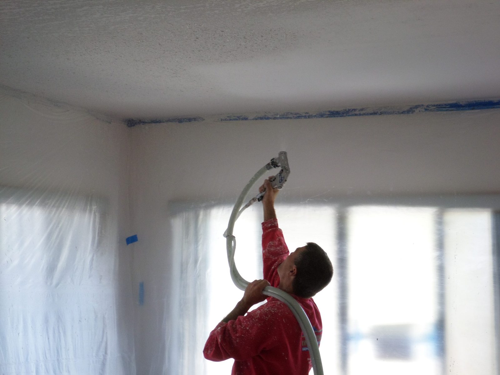 Jeff Handyman spraying ceiling texture with a hopper gun on a Palm Coast project