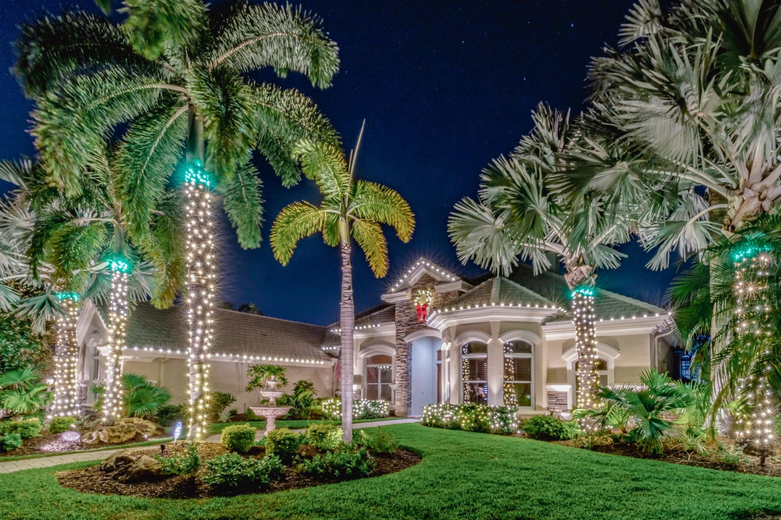 Florida home at night decorated with Christmas lights along the roofline and lit palms by Jeff Handyman