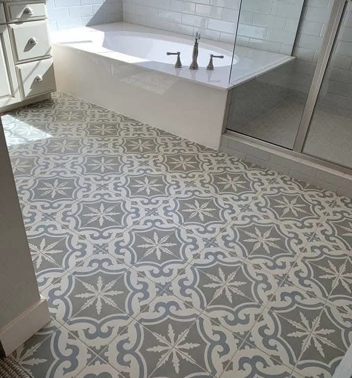 Gray and white encaustic medallion tile floor surrounding a freestanding tub by Jeff Handyman