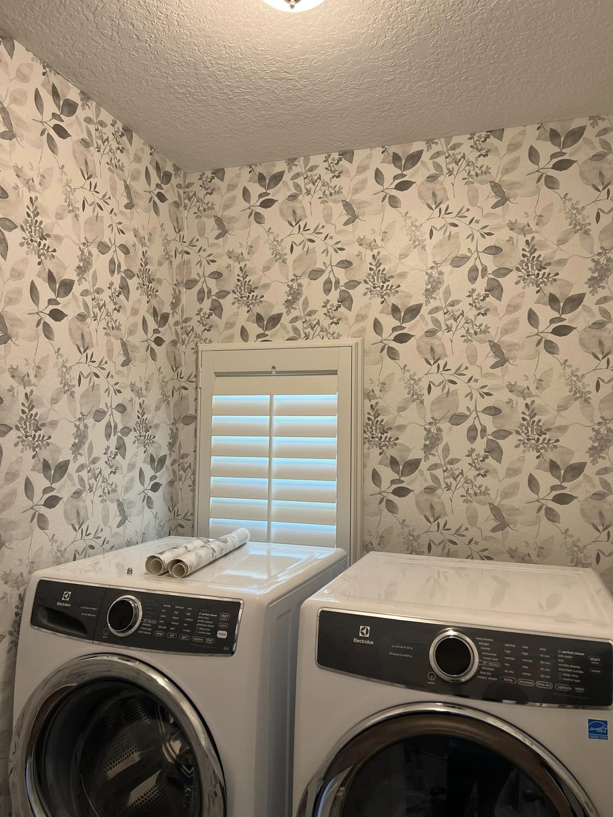 Floral wallpaper installed in a laundry room above stacked washer and dryer by Jeff Handyman