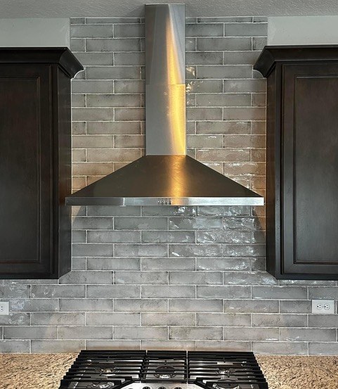 White marble kitchen backsplash with custom range hood and stainless steel stove
