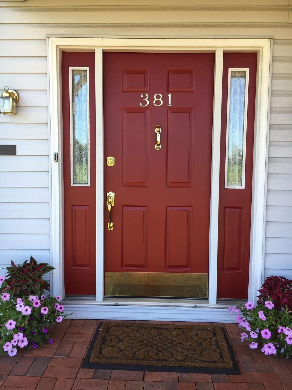 Classic red exterior entry door with welcome mat and white siding