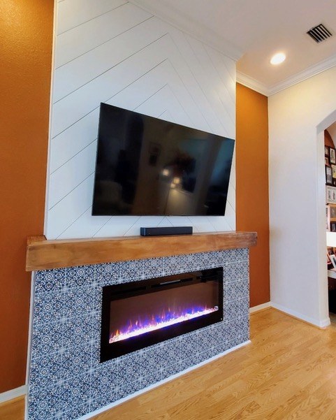 TV accent wall with white shiplap above and patterned tile fireplace surround with wood mantel by Jeff Handyman