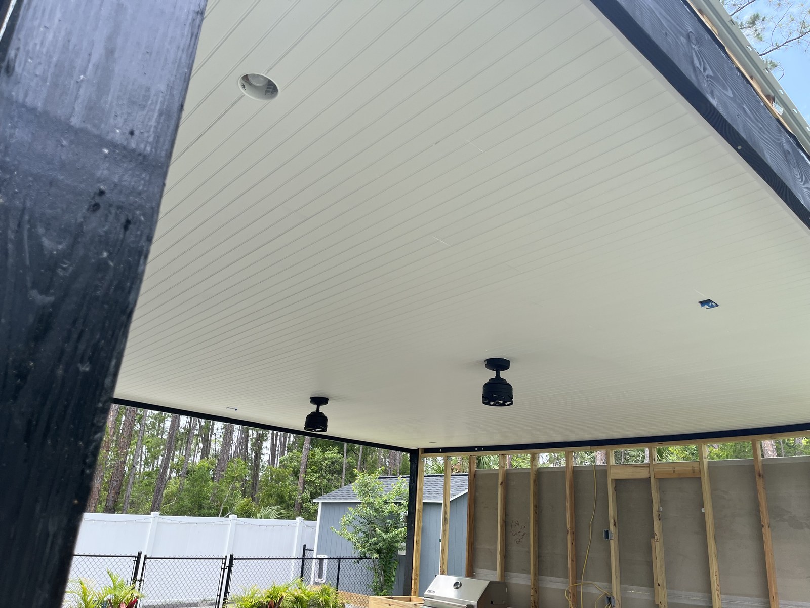 Custom white vinyl soffit ceiling install on a covered patio with black beam accent and ceiling fans by Jeff Handyman