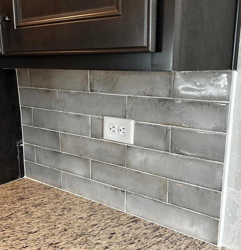 White subway tile kitchen backsplash with custom outlet placement and quartz countertop